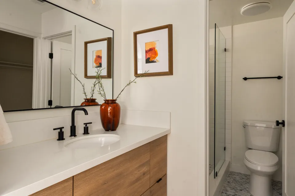 Bathroom with a wood vanity, black fixtures and a glass shower, Oceanside home