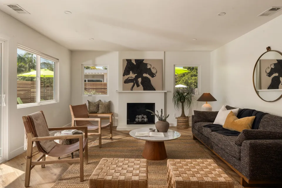 Living room with a white fireplace, a round mirror and leather chairs, Oceanside home