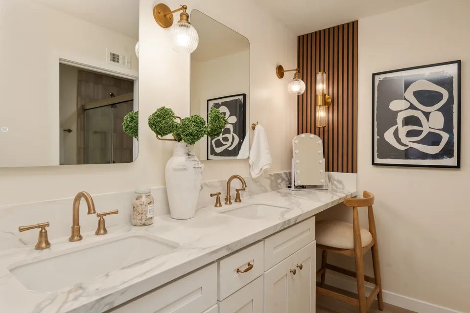 Bathroom with a double vanity, brass faucets and sconces, and a wood slat accent wall, renovated San Diego home