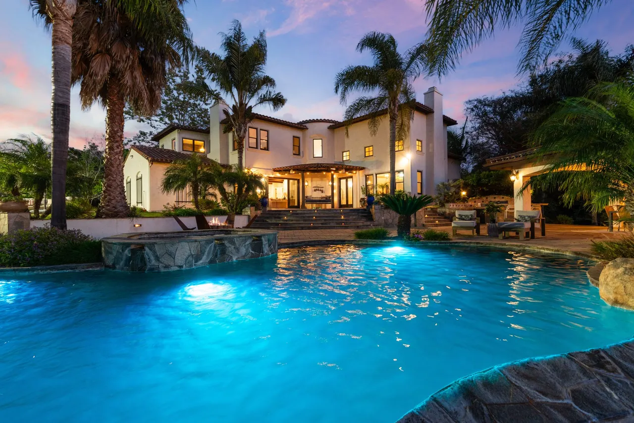 Pool and home at dusk, framed by palms