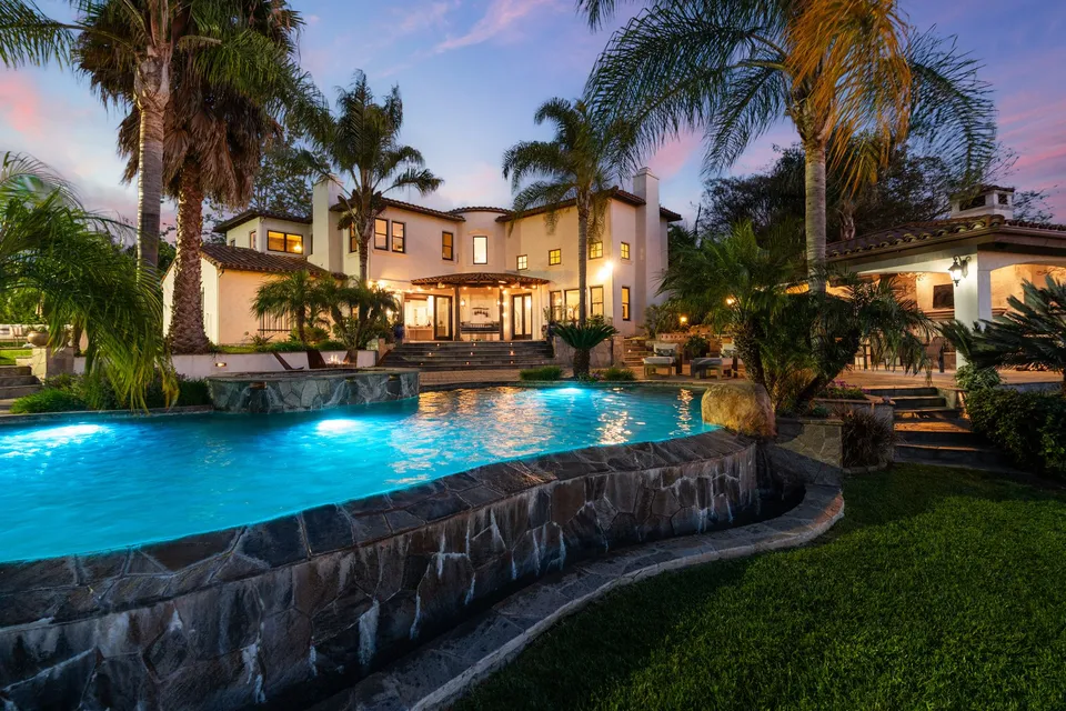 Stone-edged pool and lawn below the home at dusk
