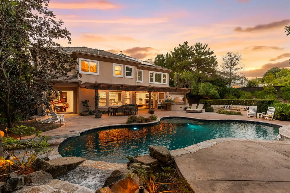 Pool, waterfall and the back of the home at sunset