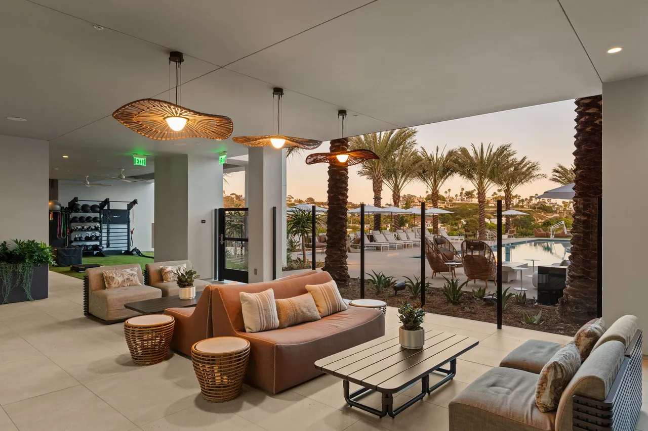 Clubhouse lounge with woven pendant lights, open to the pool deck